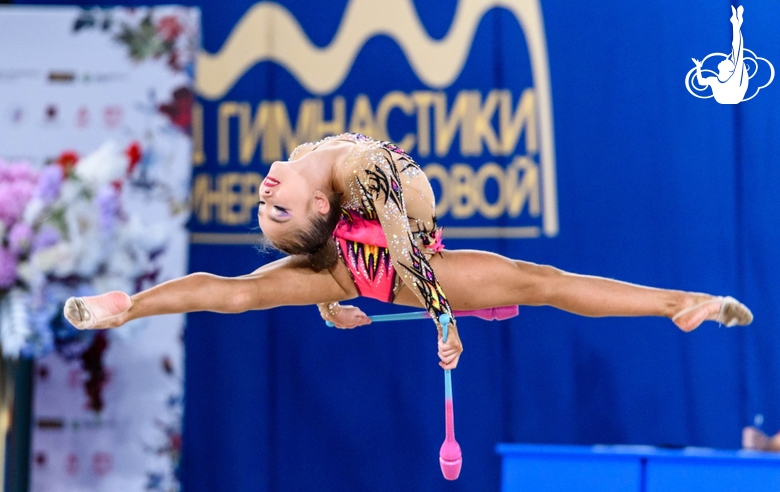 Ксения Савинова выполняет прыжок в шпагат во время упражнения с булавами