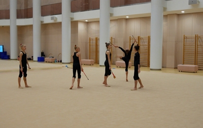 Alina Kabaeva explains to group exercise gymnasts of the Academy how to catch the club in a jump with a step at the workout