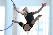 Elvira Belyaeva does a split jump during an exercise with a hoop