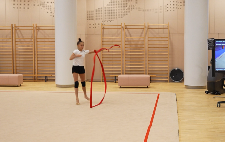 Alina Kabaeva and coach Alina Gusarova are helping Mariia Borisova to polish her boomerangs in the ribbon exercise