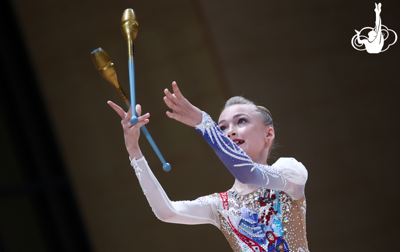 A gymnast performs an element with clubs during an assessment training