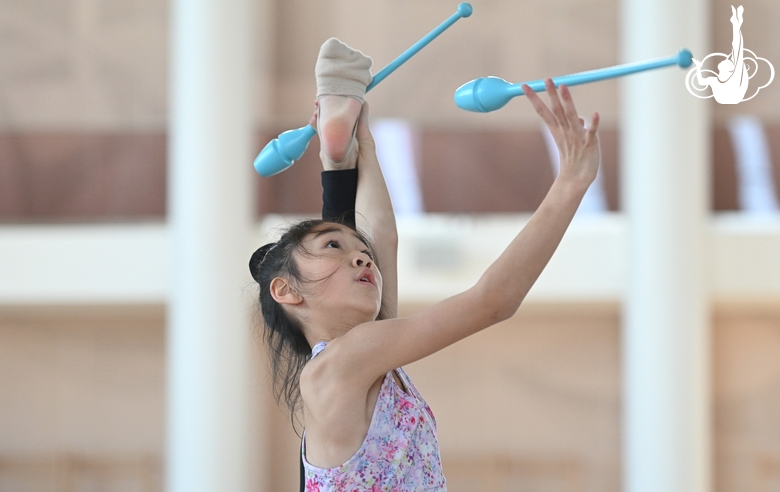 A gymnast from China during the exercise with clubs when training