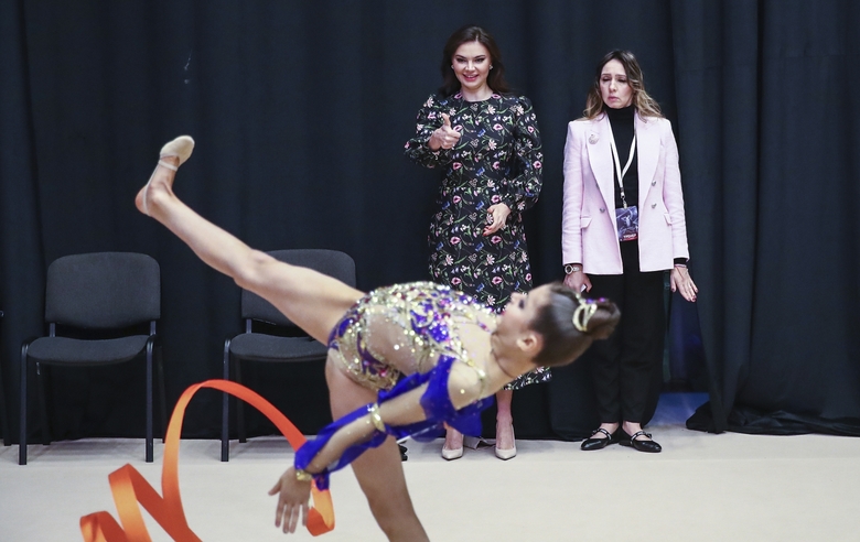 Olympic champion Alina Kabaeva offers support to a young gymnast during a performance