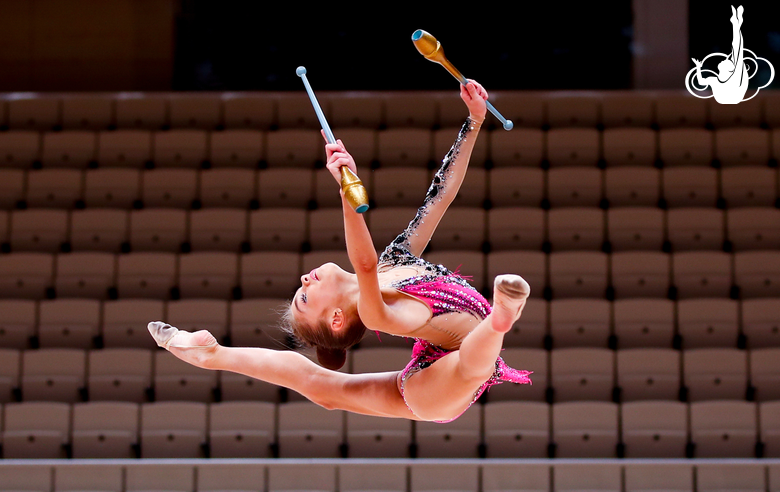 Split jump with clubs performed by a young gymnast