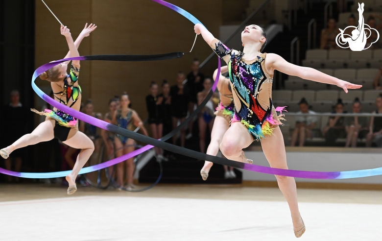 Gymnasts do an exercise with a ribbon during a group performance at the Formula of Victory competition