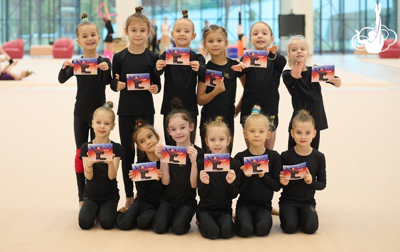 Young gymnasts hold postcards with autographs of Olympic champion Alina Kabaeva