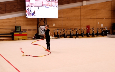 Олимпийская чемпионка и тренеры помогают Арине Ковшовой скорректировать упражнение с лентой, чтобы избежать потери баллов