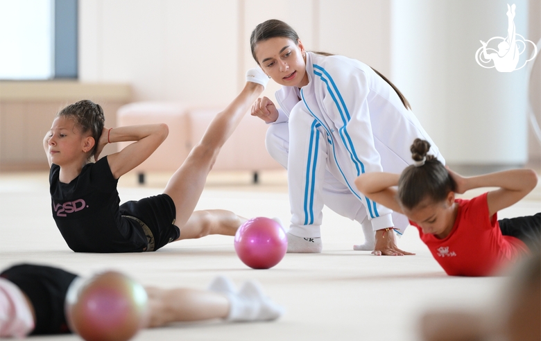Coach Ekaterina Lots with gymnasts during practice at the training camp in the Academy