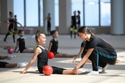 Coach Ekaterina Lots with gymnasts during practice at the training camp in the Academy