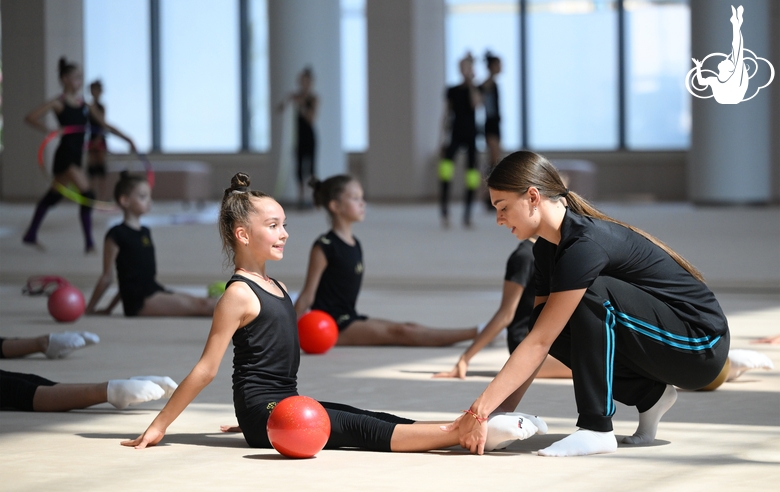 Coach Ekaterina Lots with gymnasts during practice at the training camp in the Academy