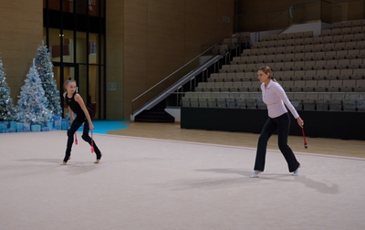 Тренеры и олимпийская чемпионка Алина Кабаева помогают Яне Заикиной отработать упражнение с булавами