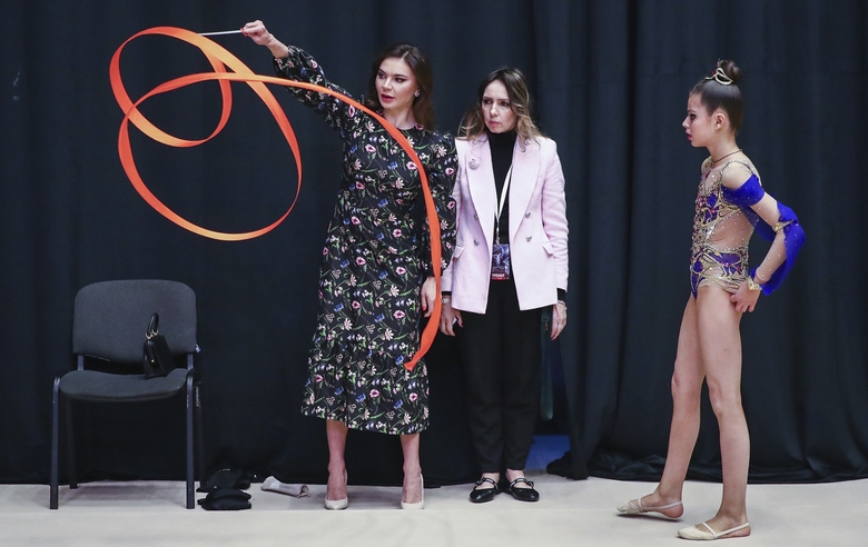 Olympic champion Alina Kabaeva explains the ribbon exercise technique to a young gymnast