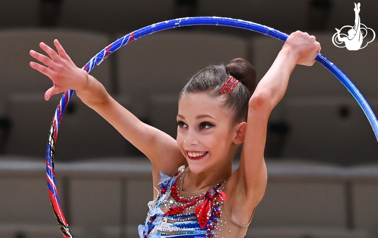 Happy gymnast does an exercise with a hoop during a performance at the Way to Victory tournament