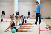 Coach Ekaterina Lots with gymnasts during practice at the training camp in the Academy